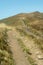 Grass Covered Mountain Bathed in Sunlight. Blue Sunny Cloudless Sky. Green Footpath.