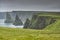 Grass pastures, cliffs and sea stacks at Ducansby Head near the town of John O`Groats in Scotland, United Kingdom on a foggy