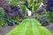 Grass path leading to stone stairs in a landscaped garden