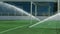 Grass sprinkler on football field. Soccer arena water irrigation. Watering grass