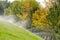 Grass and trees are watering with sprinkler system in autumn