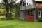 Grassy field with small converted barn with red doors and windows