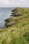 Grassy headland or peninsula with coastguard lookout in distance, portrait