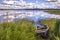 The grassy shore of the lake with an old wooden boat