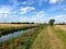Grassy towpath alongside small canal with fields and blue skies in England