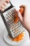 Grate fresh carrots, the cook rubs carrots on a grater