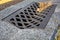 Grate with holes for drainage of storm water from a concrete ditch.