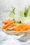 Grated carrot on wooden table with small grater, fennel and green leaves