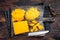 Grated and diceded Cheddar Cheese on a wooden chopping board. Dark wooden background. Top view