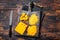 Grated and diceded Cheddar Cheese on a wooden chopping board. Dark wooden background. Top view