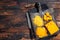 Grated and diceded Cheddar Cheese on a wooden chopping board. Dark wooden background. Top view. Copy space