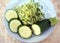 Grated and sliced small green zucchini on the plate, top view