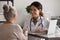 Grateful aged female patient shake hand of young woman doctor