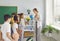 Grateful children on Teacher Appreciation Day give flowers to woman tutor stands in school room