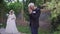 Grateful senior Caucasian groom putting hands together praying and looking at camera with blurred bride standing at