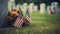 A grave with an american flag and colorful flowers are noticeable in the background for memorial day