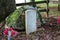 A grave with a white stone headstone surrounded by a brown wooden fence and lush green trees at McIntosh Reserve Park