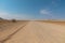 Gravel 4x4 road crossing the  desert at, in the beautiful namib Naukluft national park against blue sky. Tourism and vacations con