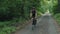 Gravel cycling. Woman riding road bicycle in forest. Cyclist twists pedals on bike along single forest gravel road. Biking adventu