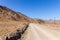 Gravel dirt road through rocky limestone Hajar Mountains and cliffs in United Arab Emirates