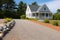 gravel driveway leading to a cape cod house with a wide porch