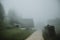 Gravel path between the mountain huts during the misty morning with the heap of wood along