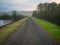 Gravel Road Along Reservoir in Foggy Forest