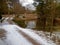 Gravel road covered in snow next to a pond