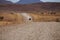 Gravel road in the desert with a car driving