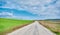 Gravel road and magnificent green grass near the road with cloudy and open sky