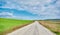 Gravel road and magnificent green grass near the road with cloudy and open sky