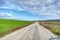 Gravel road and magnificent green grass near the road with cloudy and open sky