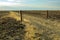 A gravel road passes through an open gate to barren farm fields in central Oregon, USA