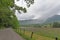 A gravel road passing through Cades Cove toward mountains and fog.