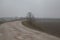 Gravel road with puddles in the italian countryside in late autumn on a foggy day