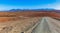 Gravel road winding through bald orange hills.