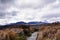 Gravel track going through desolated high land field in Central Plateau of New Zealand. Snow blanketed volcanic cone of