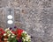 Gravestone with cross and empty plates surrounded by begonias