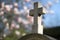 Graveyard stone cross with beautiful springtime magnolia flowers, blurred background