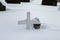 Graveyard in winter, a small wooden cross and a lantern covered in snow