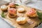 Gravlax a raw, marinated graved salmon with dill on bred roll bun with cream cheese, onion rings on tray with baking paper and