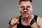 On a gray background stands a battered man in a black T shirt looking like a fighter and preparing for a fight