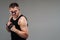 On a gray background stands a battered man in a black T shirt looking like a fighter and preparing for a fight