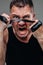 On a gray background stands a battered man in a black T shirt looking like a fighter and preparing for a fight