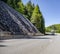 Gray big rig semi truck with semi trailer running on the winding mountain road with safety net against falling rocks on the side