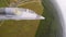 A gray blue combat plane fly over a road in field and rolls to the left. A fighter moves over a green forest