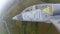 A gray blue training plane fly over green fields and rolls to the right. Fighter turn against the background of green fields