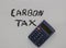 A gray calculator on top of a white sheet of paper that says, carbon tax