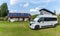 Gray camper van parked at a campground with a sanitary facilities building with solar panels behind