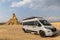 Gray camper van parked in the middle of the desert and wilderness with copy space